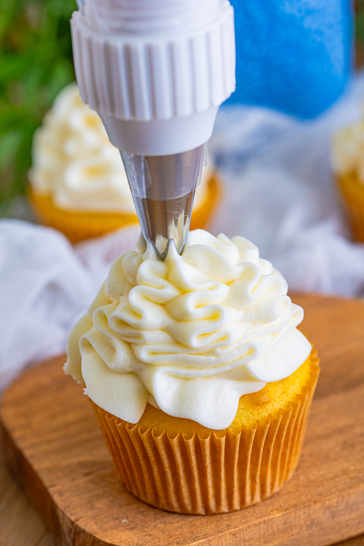 piping Cream Cheese Frosting on top of a cupcake