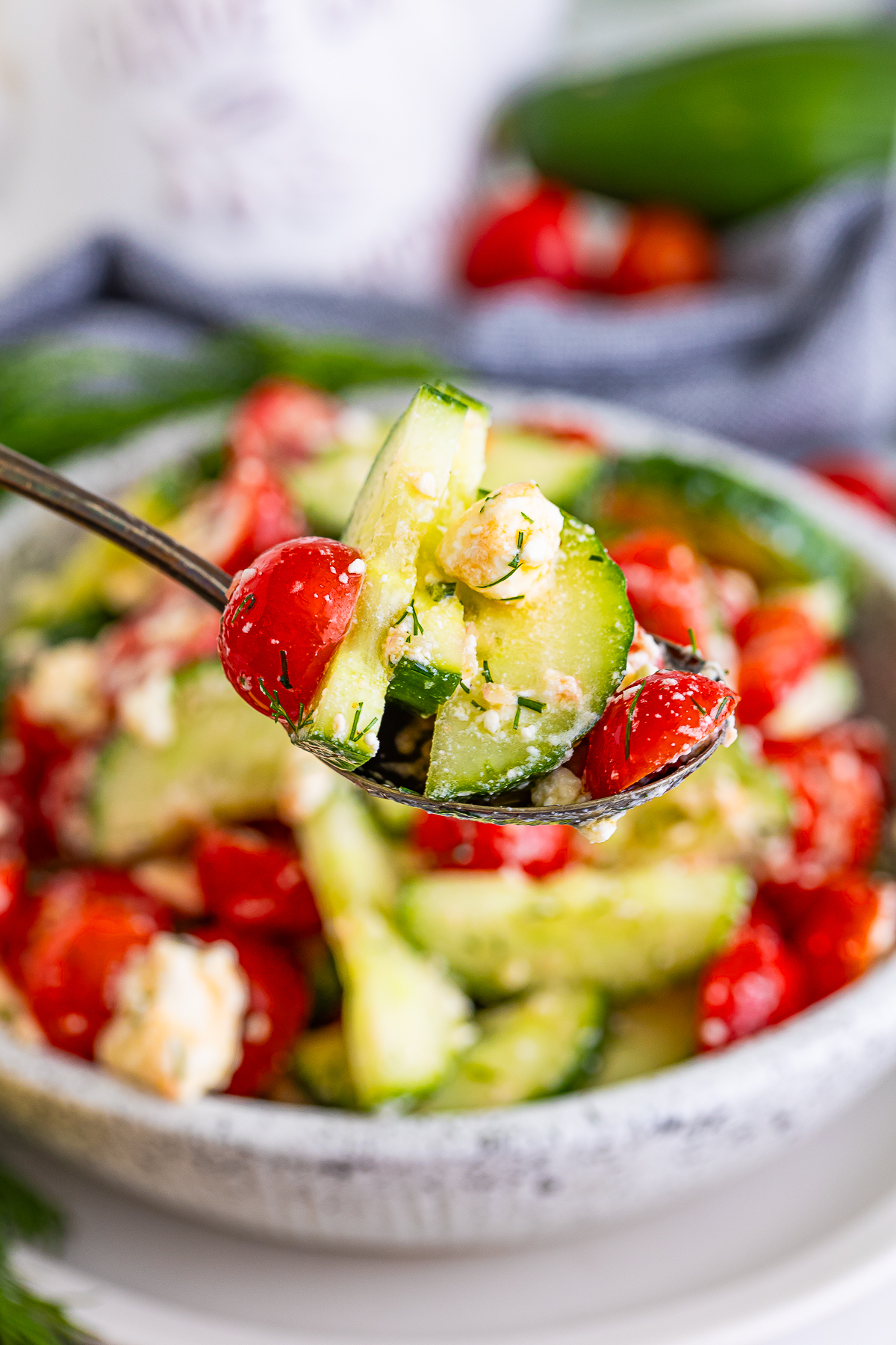 a spoon holding up a bite of Cucumber Tomato Feta Cheese Salad in air