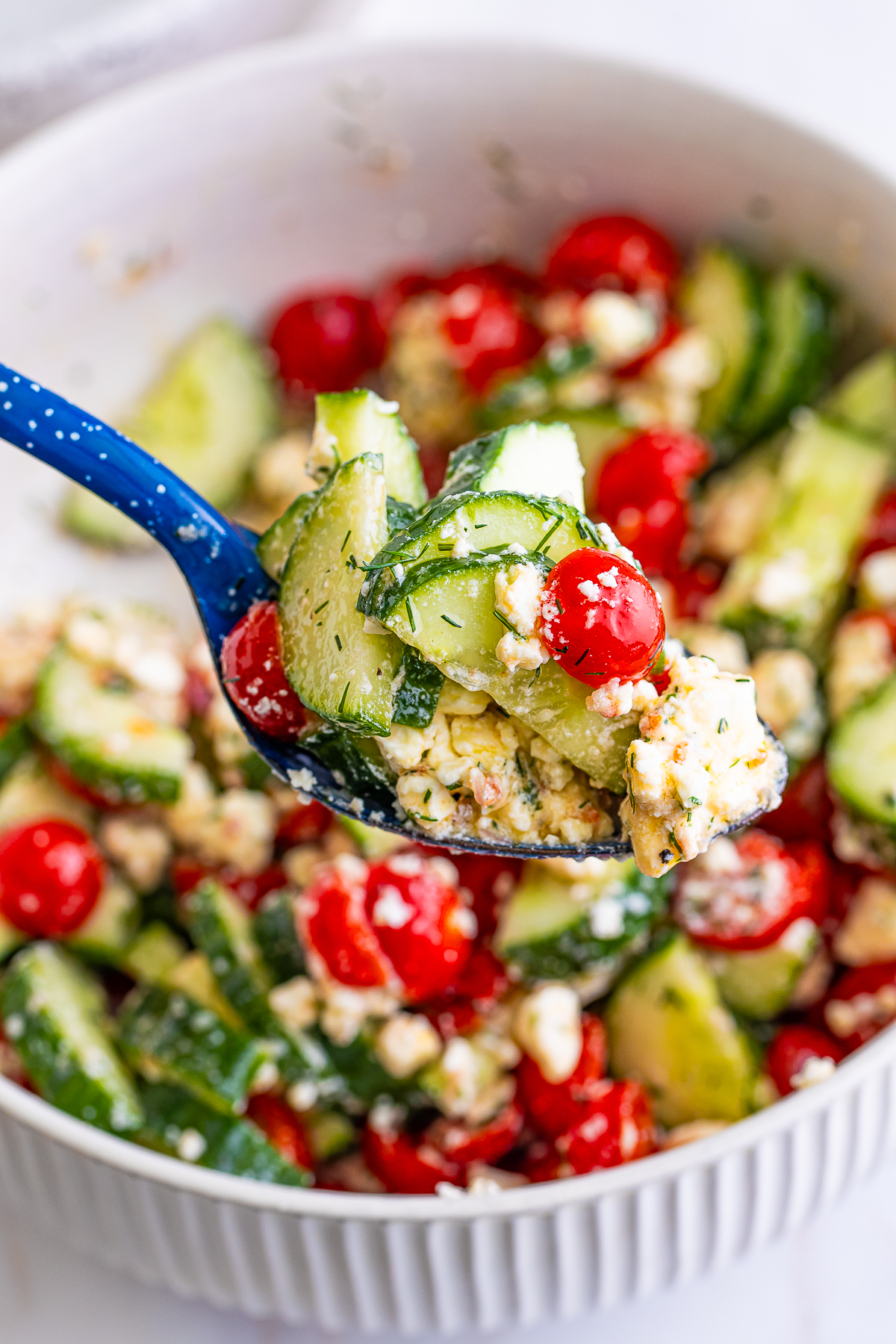 a spoon holding up a portion of Cucumber Tomato Feta Cheese Salad in air