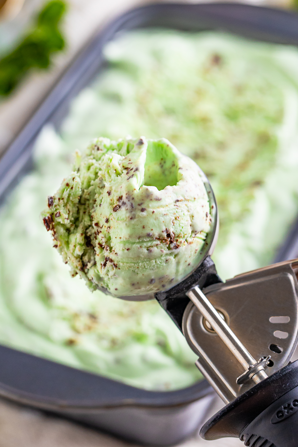mint chocolate chip ice cream in an ice cream scoop being held in air