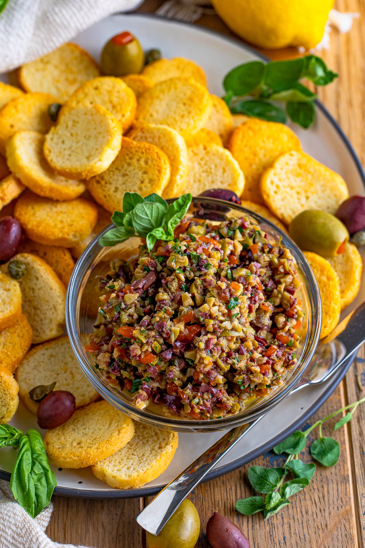 overhead image of olive tapenade in a glass bowl on serving platter
