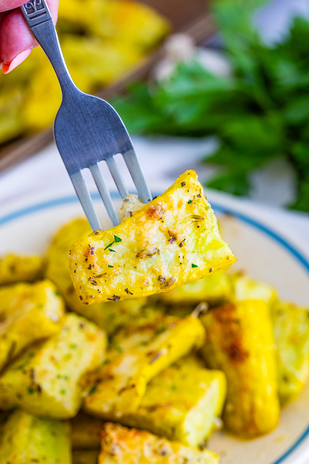 a fork holding up a piece of Roasted Yellow Squash in air