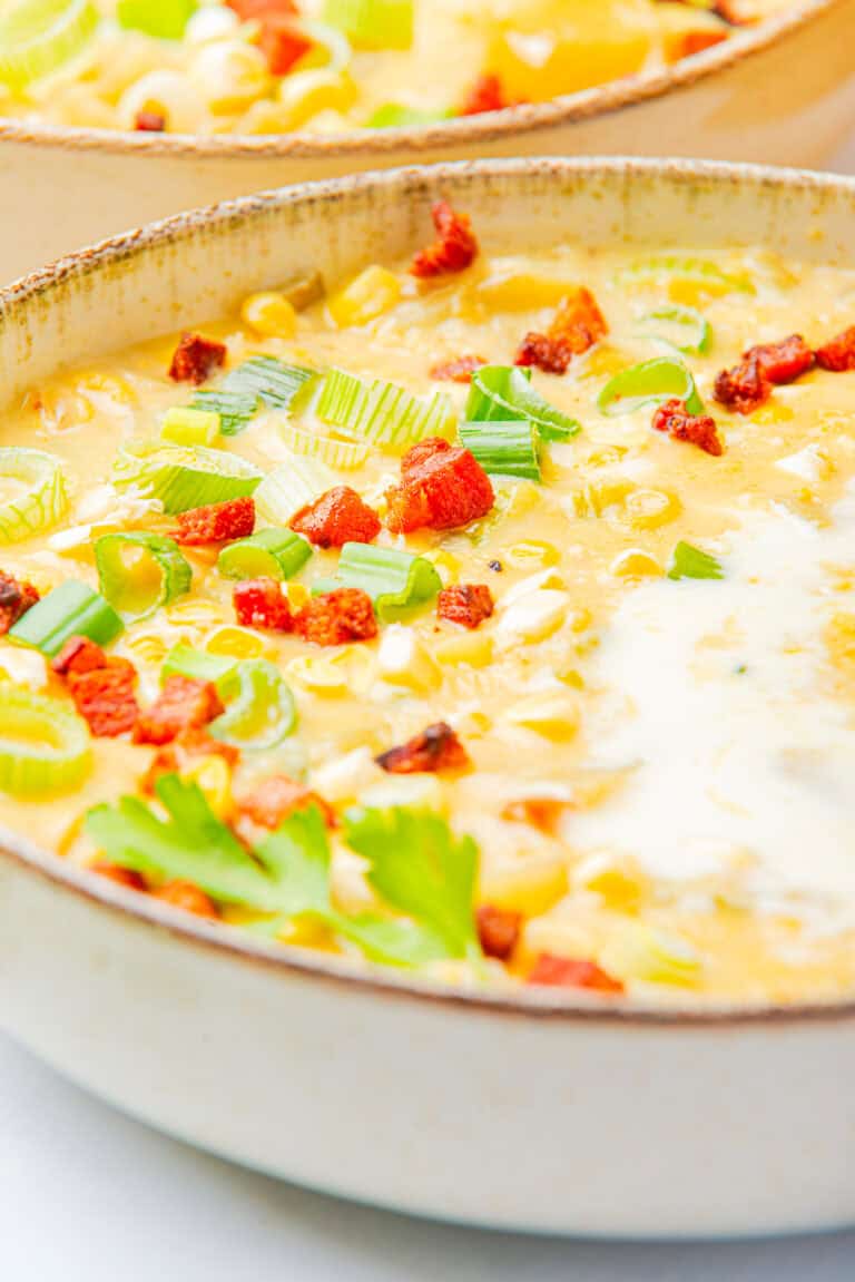 A pot of creamy corn chowder topped with crispy bacon and green onion.