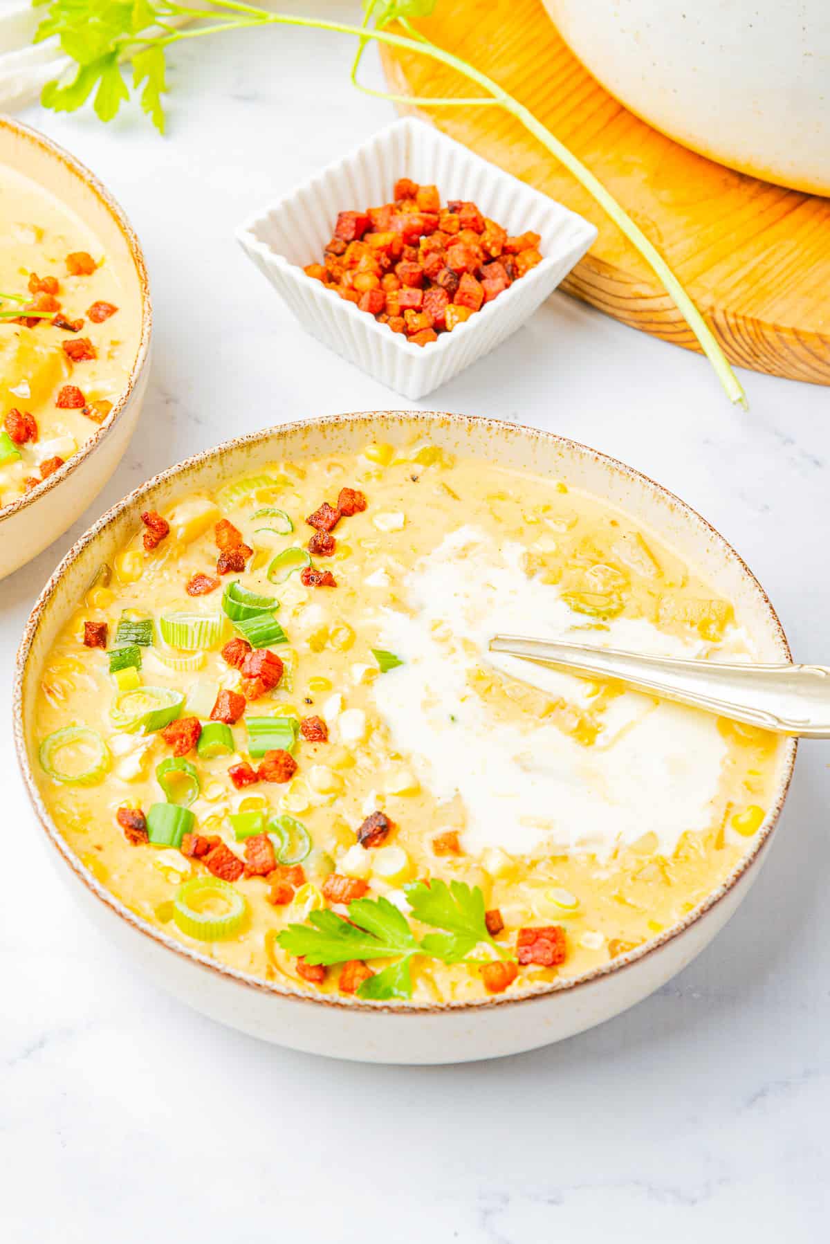 Corn Chowder served in a tan bowl on marble table top