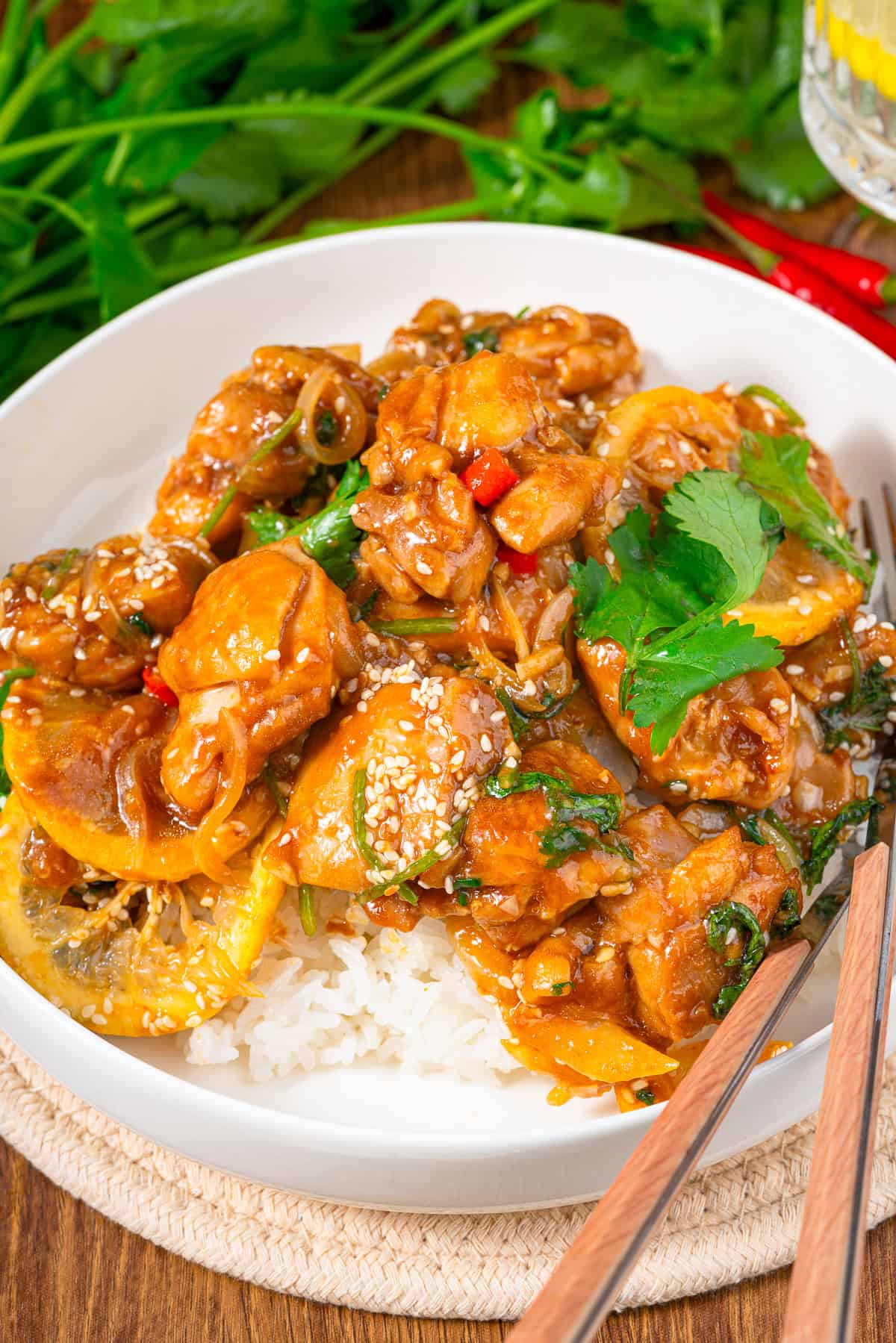 Asian lemon chicken served over white rice in a bowl with chopsticks and fresh cilantro.