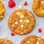 White Chocolate Raspberry Cookies on parchment paper studded with white chocolate chips and fresh raspberry swirls.