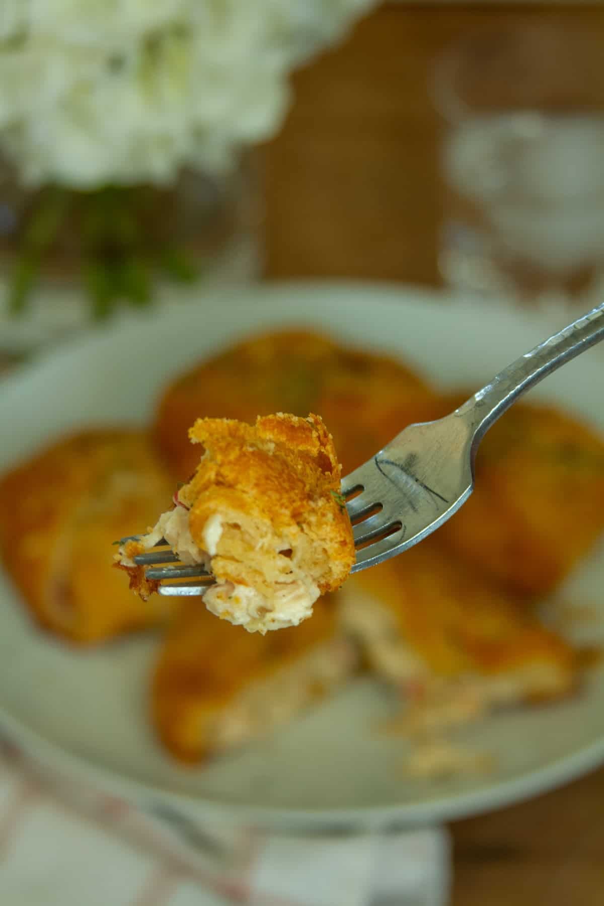 A picture of a large bite of the chicken crescent roll front and center of the picture