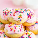 A pile of soft frosted lofthouse cookies with pastel frosting and rainbow sprinkles.