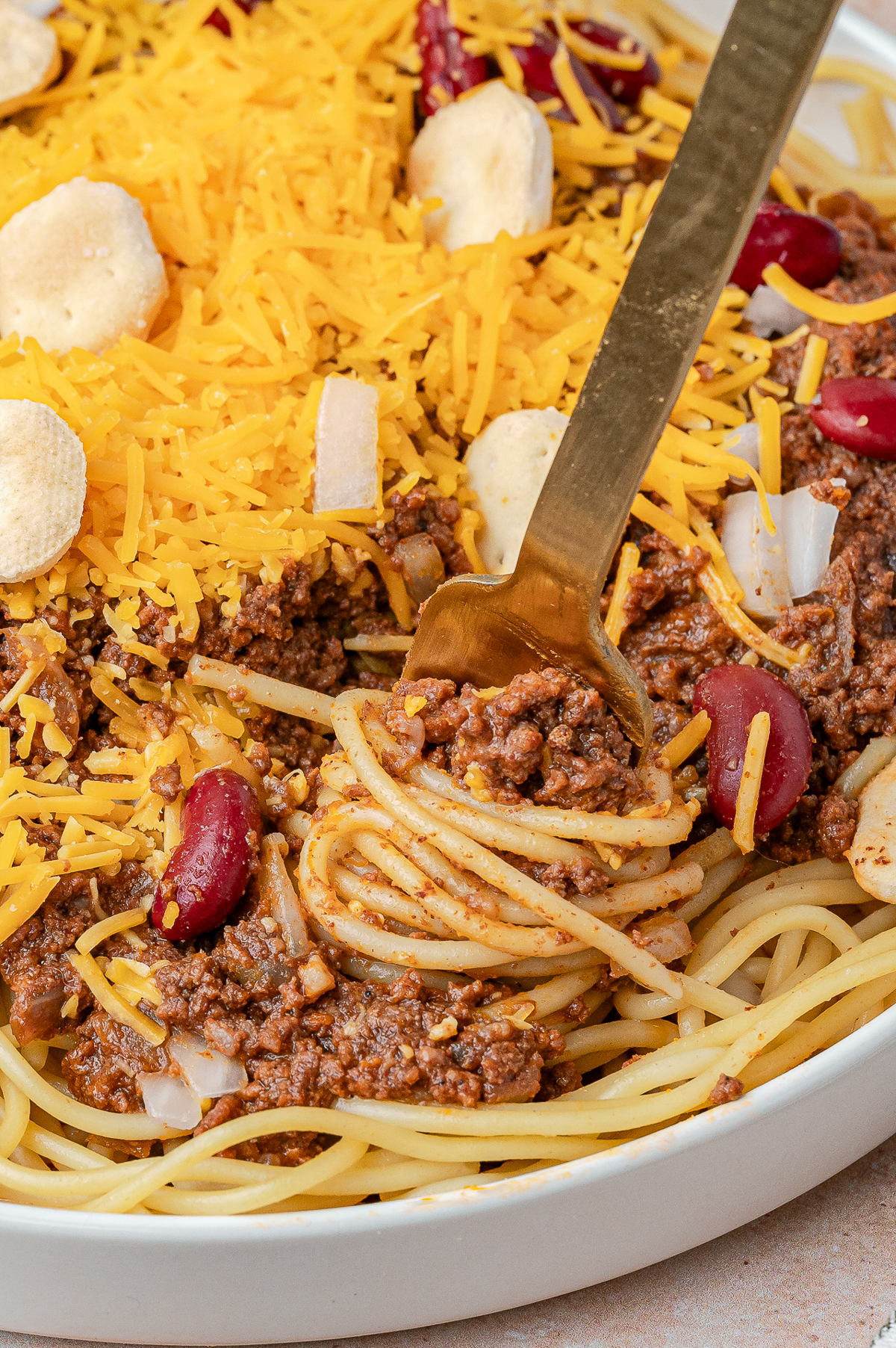 A picture of a fork swirled full of chili and spaghetti.