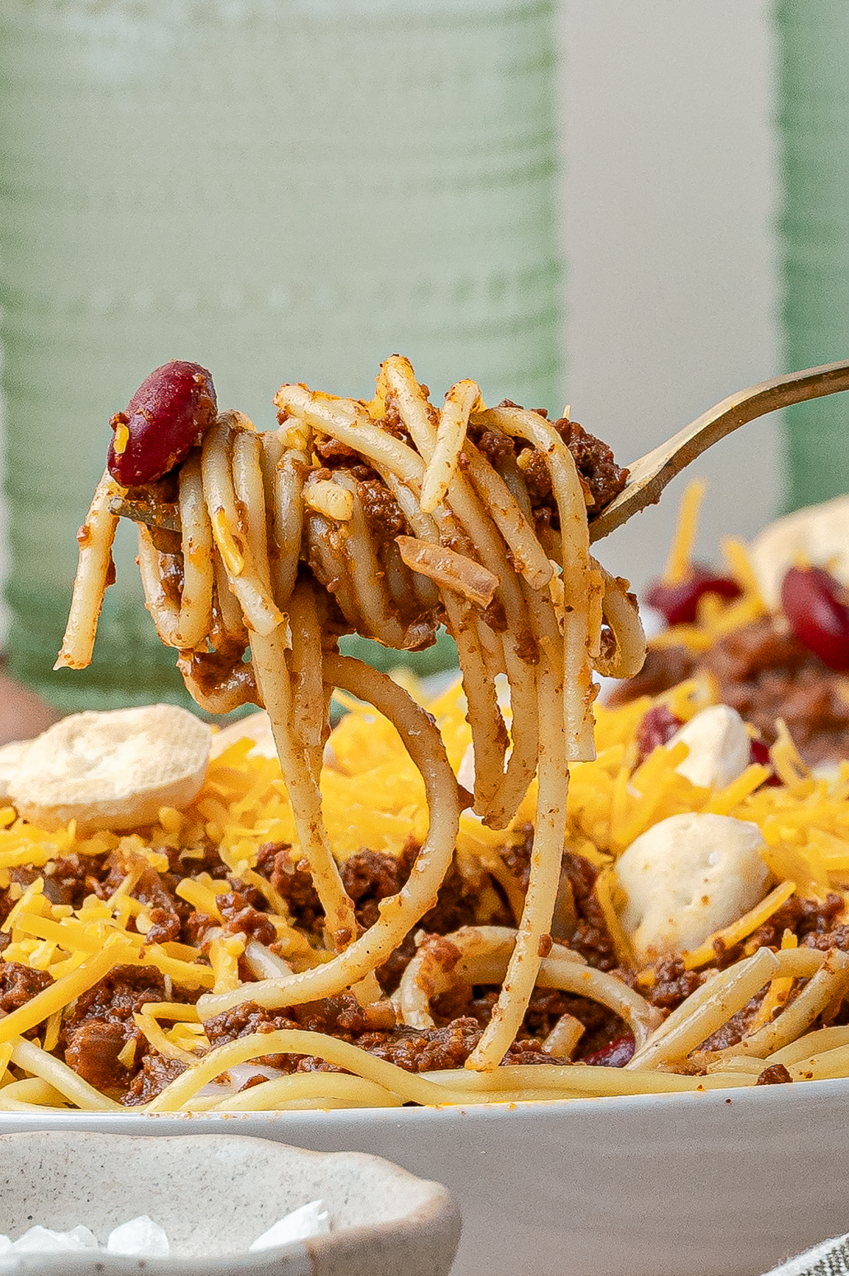 A picture of the spaghettin loaded with chili and the fork is held above the made recipe.