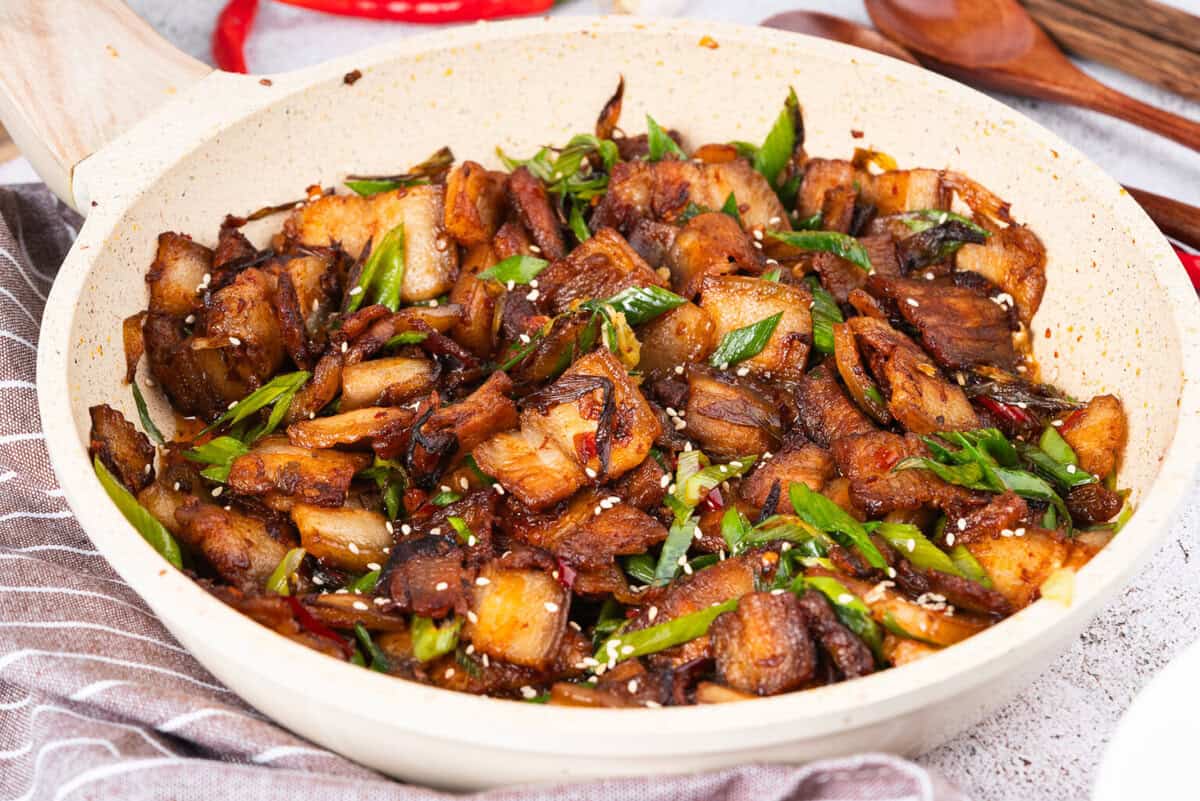 If you love bold flavors and quick dinners, Twice Cooked Pork might become your new best friend.
In China’s Sichuan Province, this dish is as famous as mapo tofu or red‑braised pork.
The Chinese name is hui guo rou, which means “returned‑to‑the‑wok pork.”
That’s because the pork belly really is Twice Cooked Pork, here: first it’s gently boiled, and then it’s hit with high heat in a sizzling stir fry!