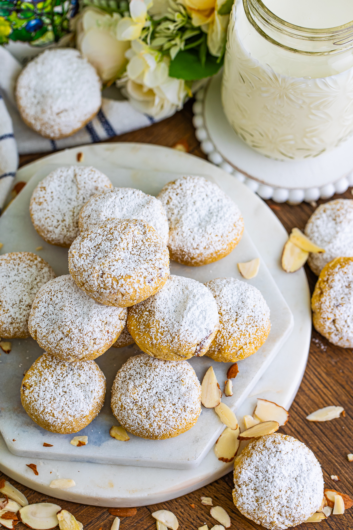 This picture is an overhead picture of the almond cookies covered in powerded sugar with a glass of milk
