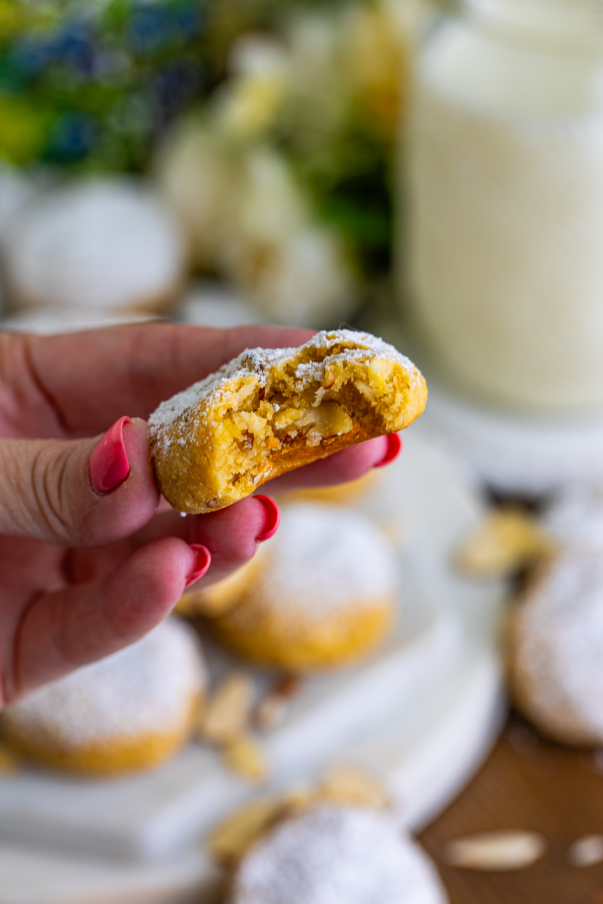 This is the final picture of an Almond cookie with bite taken out of it in the hand of the recipe creator.