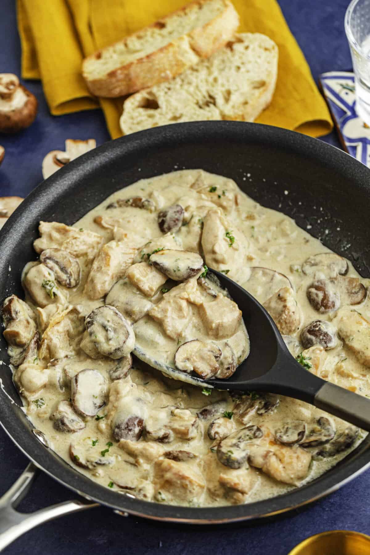 Freshly finished the chicken stroganoff is still in the pan used to cook the recipe. There is a spoon filled with the recipe