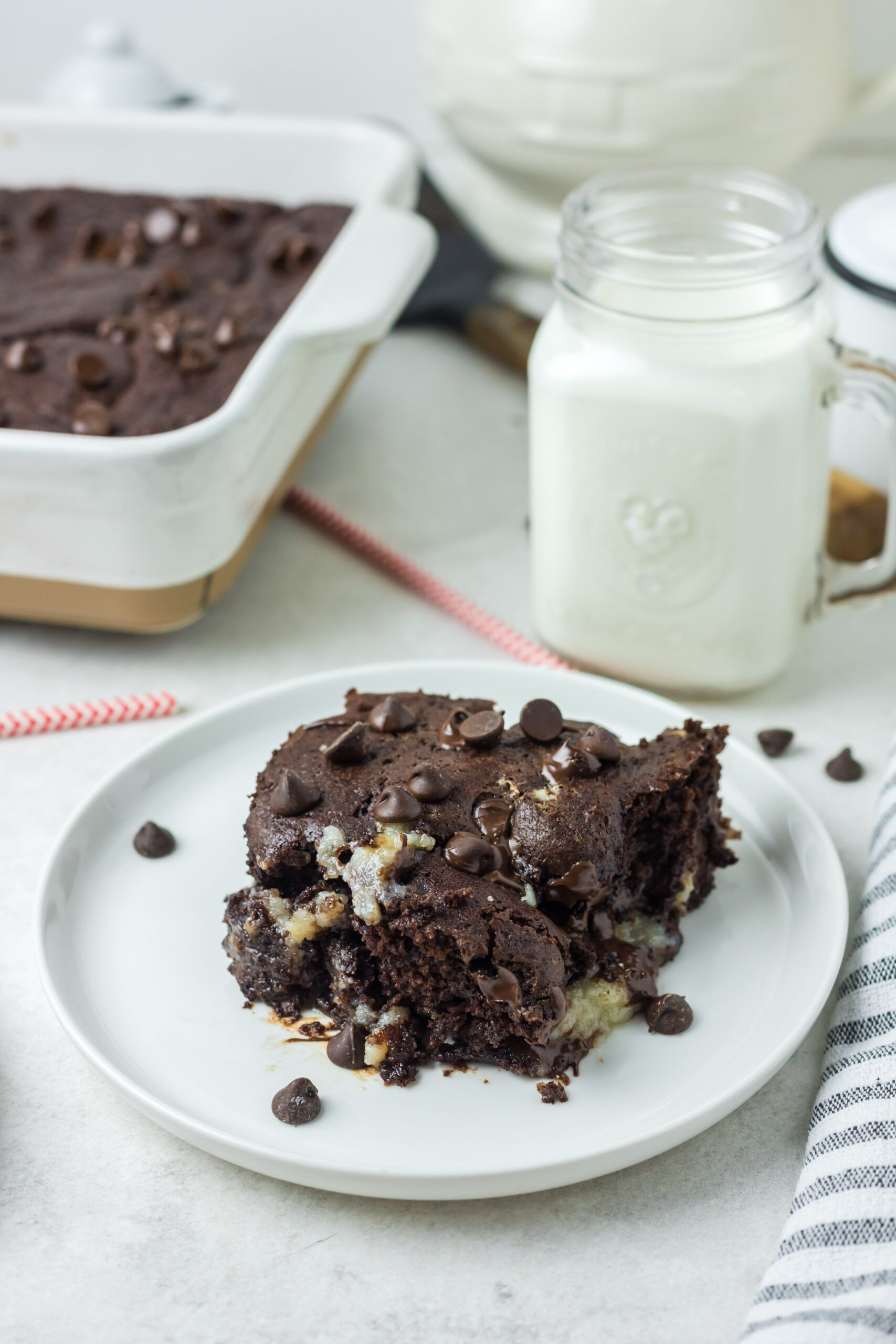 This is a picture of the cake with a bite taken out of it.  There in a glass of milk in the background and the rest of the cake in the background