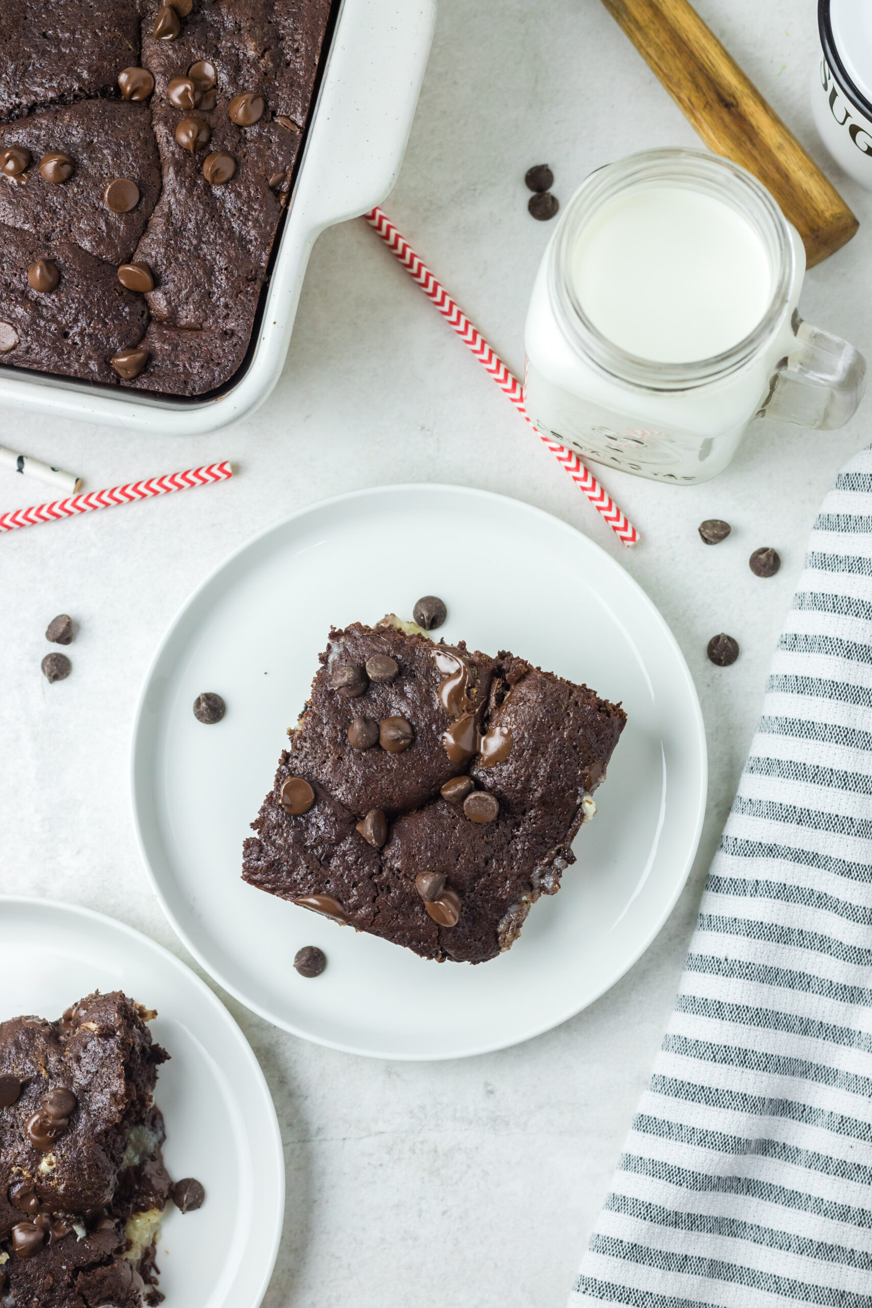 This is a pitcture of a piece of the chocolate earthquake cake with sprinkles of chocolate chips a glass of milk and the remainder of the cake.