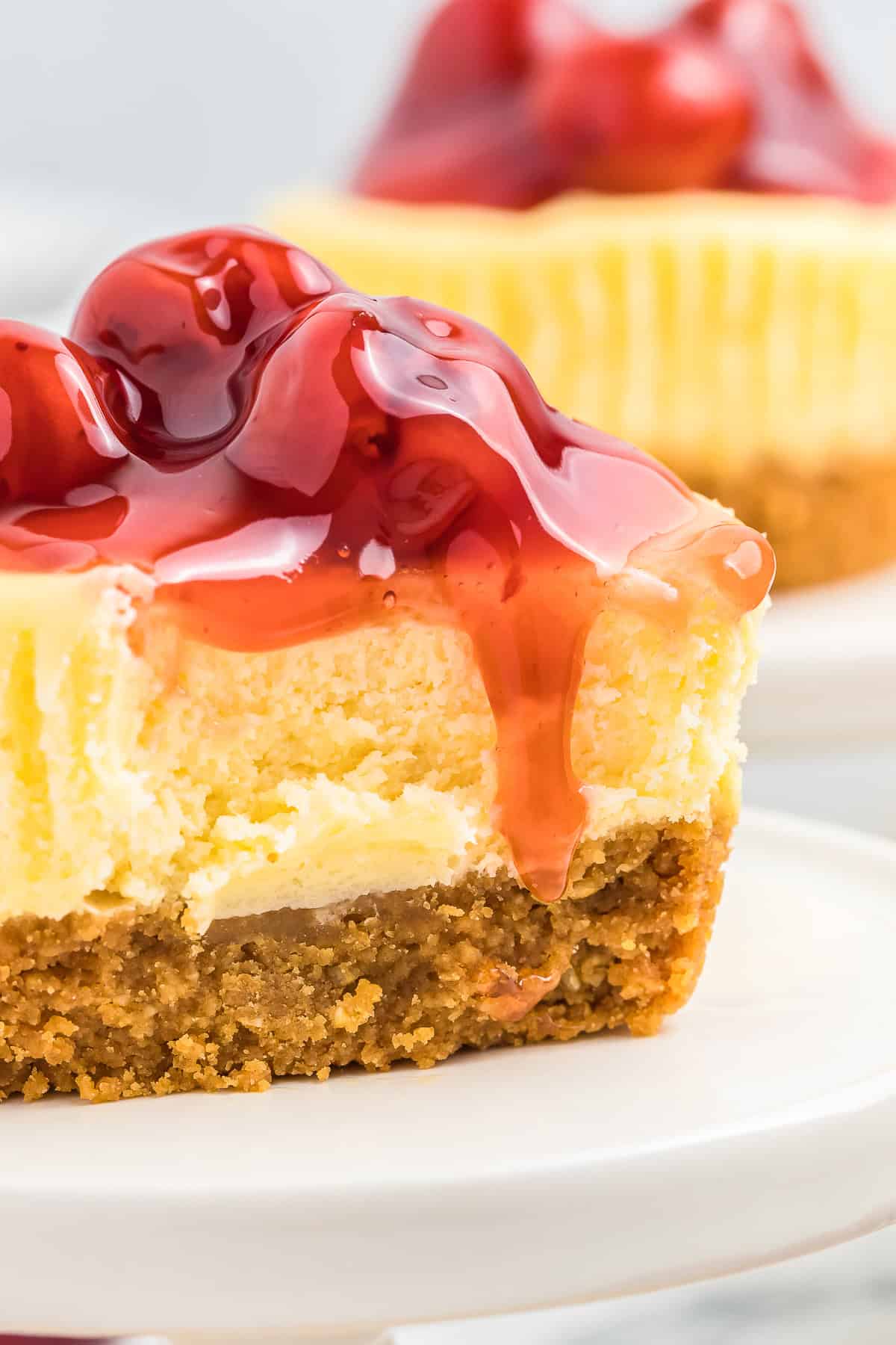 Final picture. This mini cheescake has a bite taken out of it. Clearly seen the gram cracker crust the cheescake and the cherry sauce.