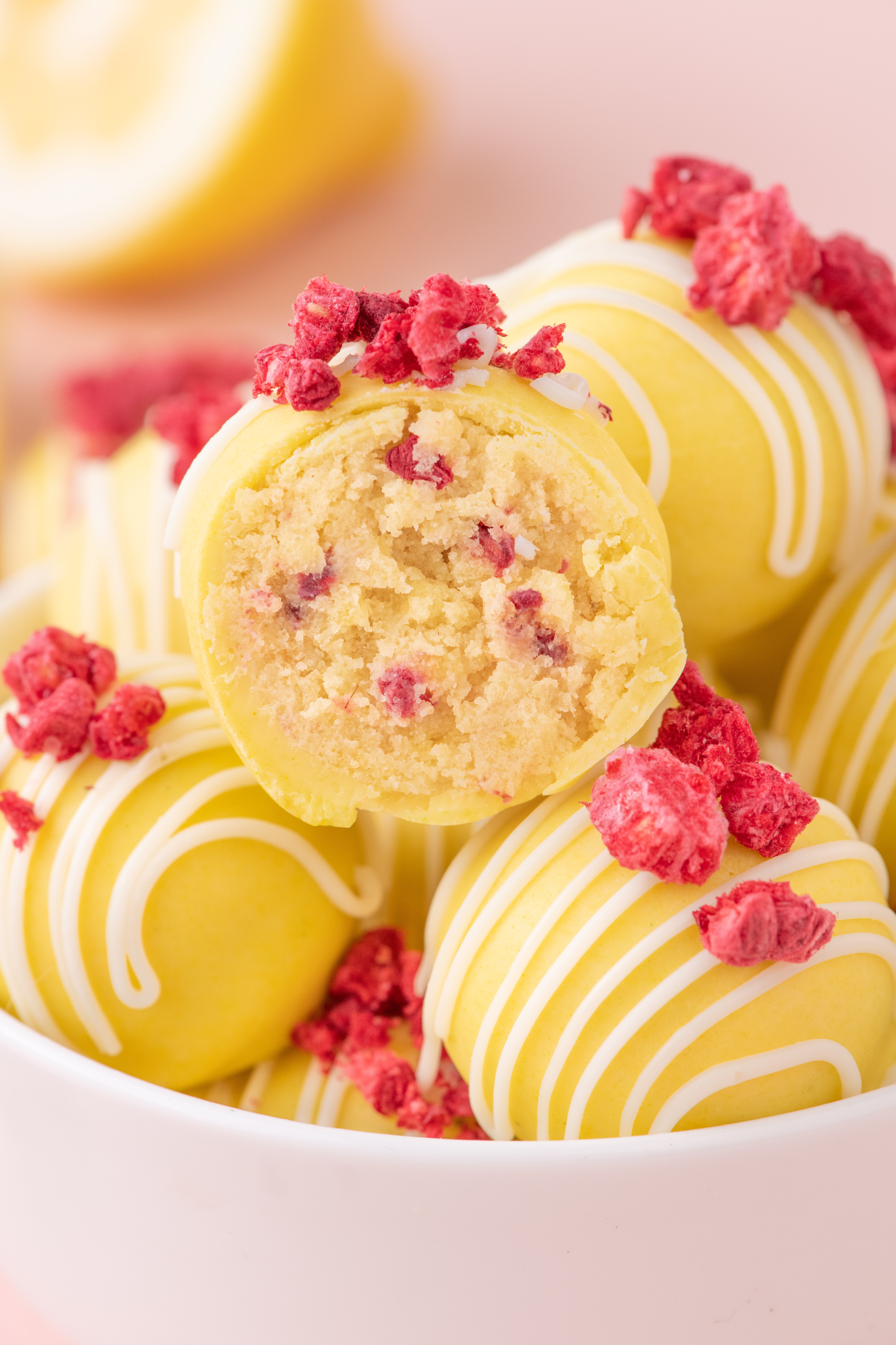 Lemon raspberry cake balls with creamy lemon cake center and raspberry pieces, coated in white chocolate. Easy spring dessert recipe.
