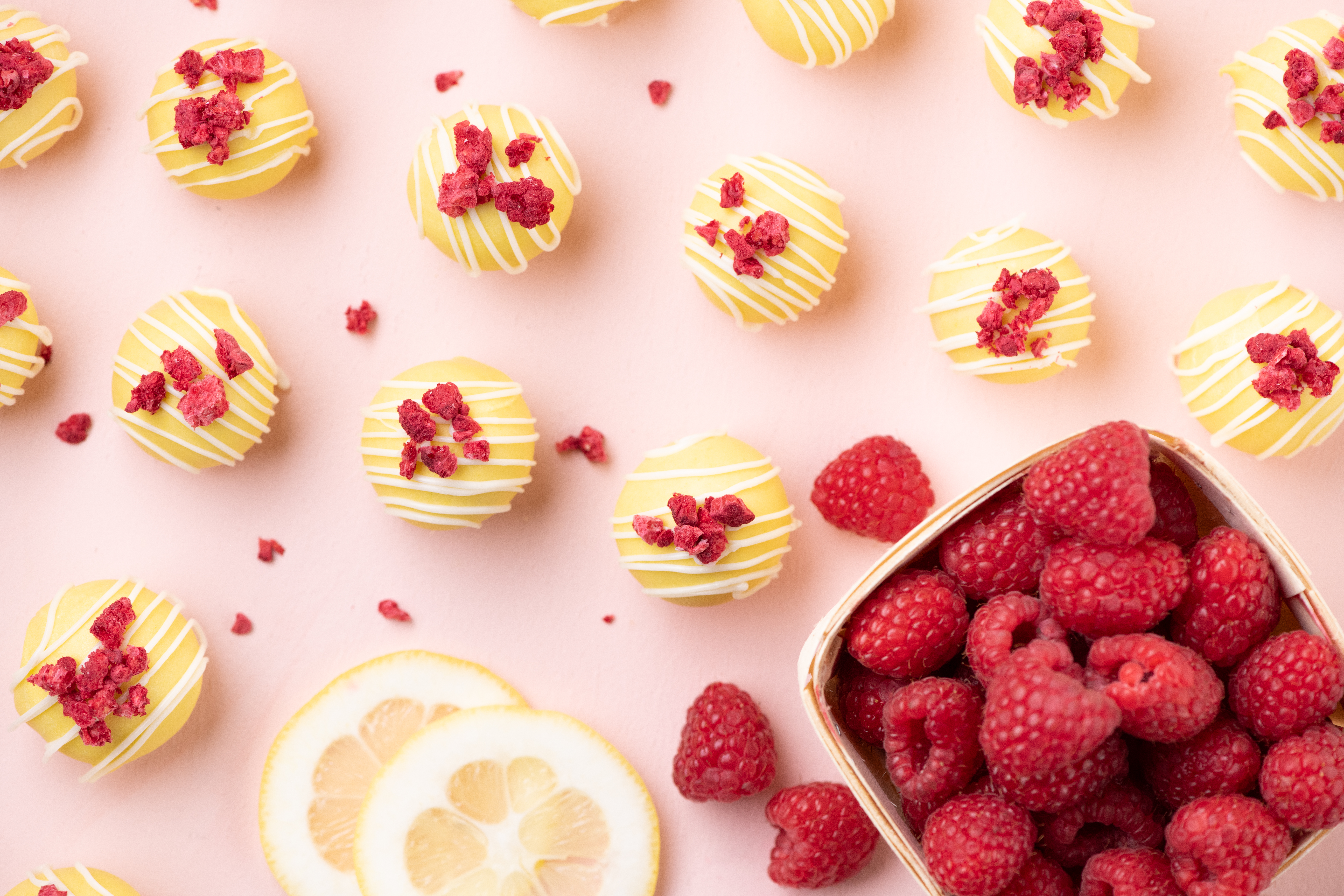 Lemon raspberry cake balls with white chocolate drizzle and freeze-dried raspberries. Bright lemon dessert recipe from This Silly Girl’s Kitchen.