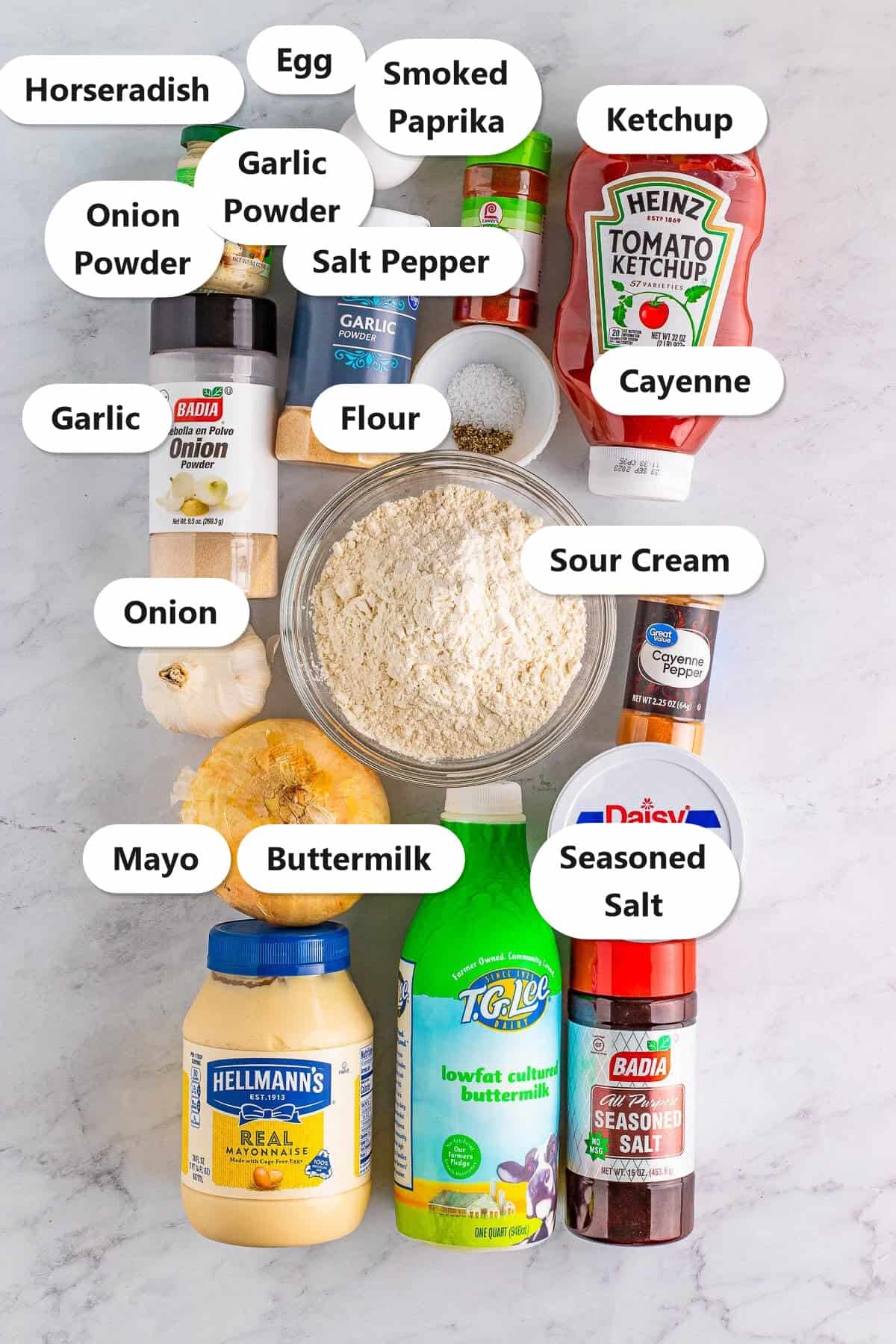 Labeled ingredients flat-lay for Crispy Onion Petals Recipe with seasoned flour, buttermilk, eggs, sweet onion, mayo, sour cream, ketchup, horseradish, garlic powder, onion powder, smoked paprika, cayenne, salt, pepper, and seasoned salt.