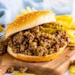 Best Copycat Maid Rite Recipe loose meat sandwich on a bun with dill pickle chips ready to serve.