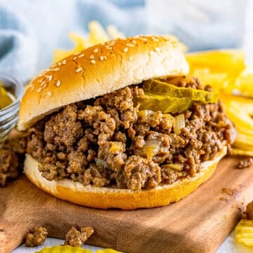 Best Copycat Maid Rite Recipe loose meat sandwich on a bun with dill pickle chips ready to serve.