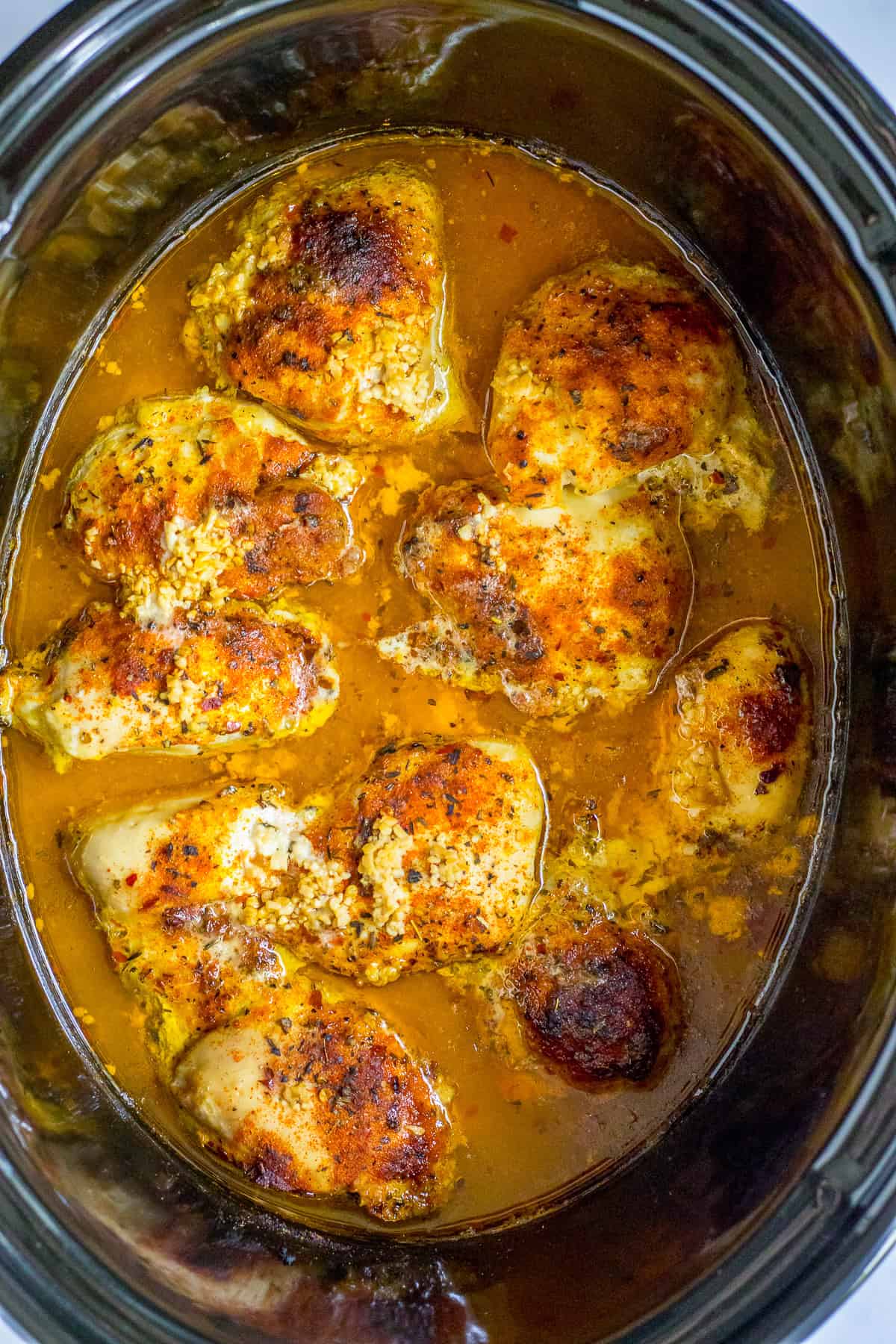 Finished slow cooker lemon chicken thighs in the slow cooker, garnished with fresh parsley and lemon slices.