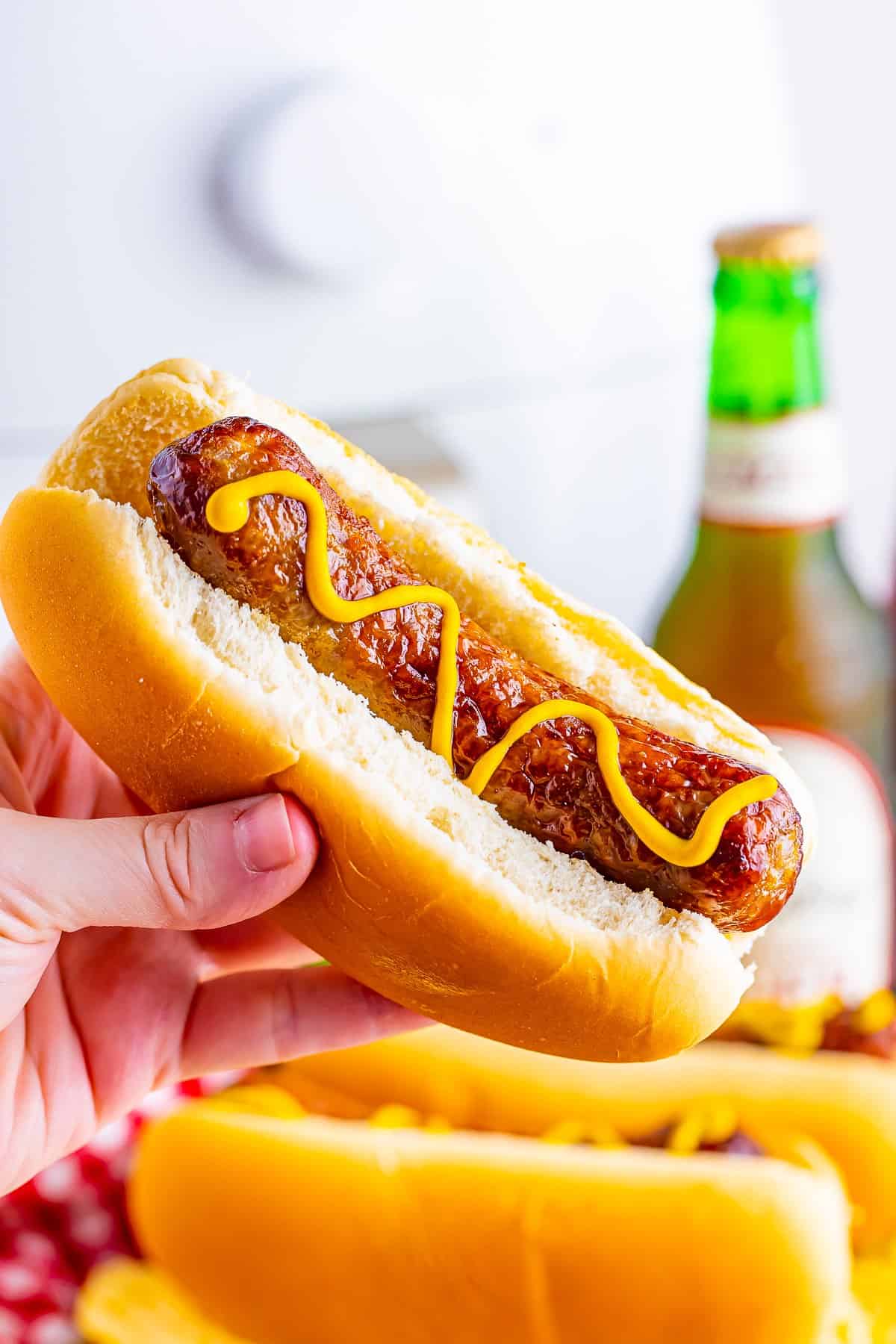 A finished plate of Johnsonville Brats in Air Fryer topped with yellow mustard and caramelized onions, ready to serve.