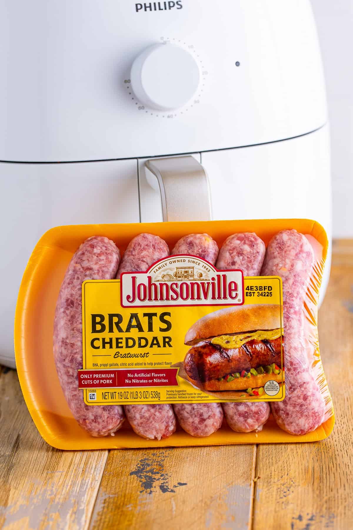 Raw Cheddar Brats arranged in an air fryer basket ready to cook for the Johnsonville Brats in Air Fryer recipe.