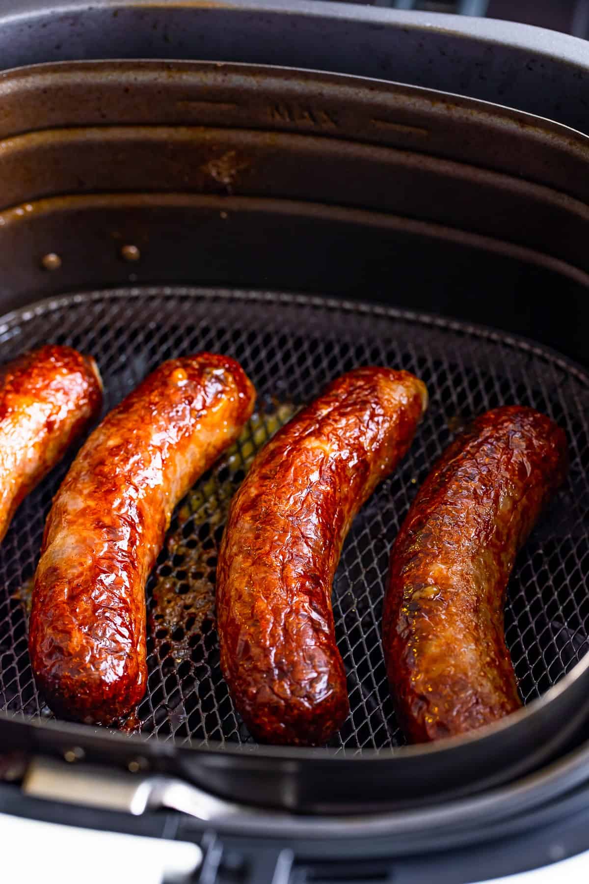Browned Johnsonville Brats in Air Fryer finished cooking in the air fryer basket.