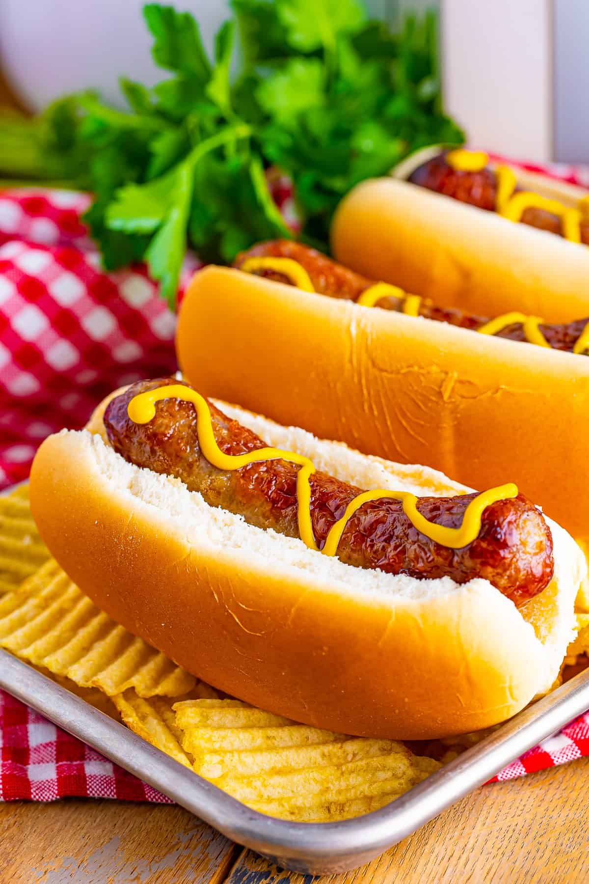 A fully assembled Johnsonville Brats in Air Fryer sandwich on a toasted bun with mustard, grilled onions, and fresh herbs.