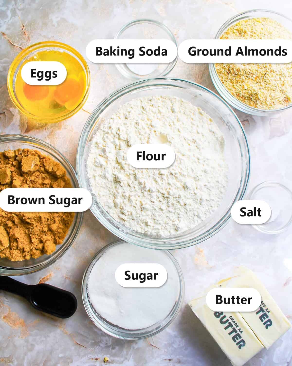 Labeled ingredients for almond cookies including ground almonds, flour, butter, brown sugar, eggs, and granulated sugar.