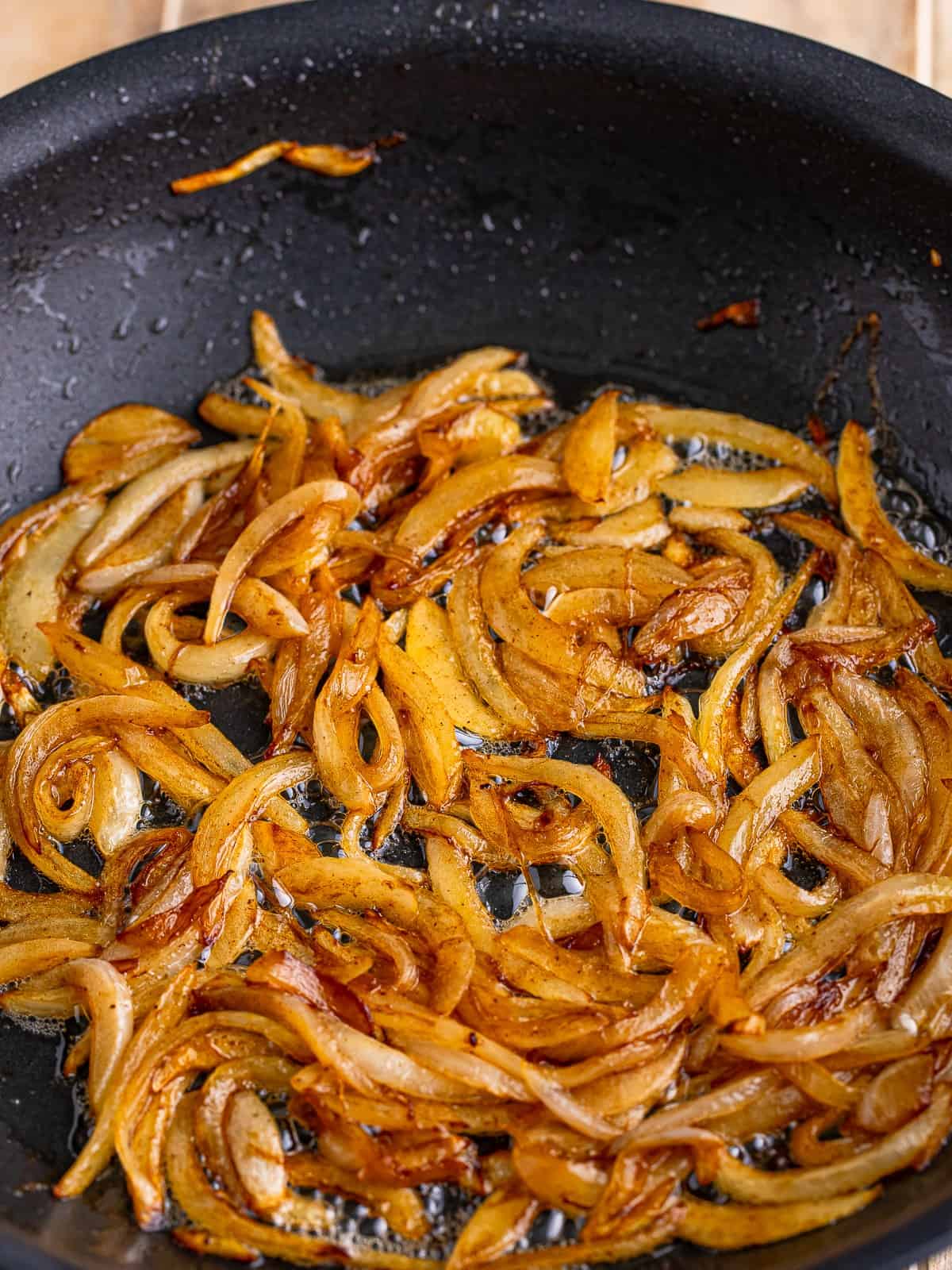 Caramelizing sliced onions in a skillet for beef tips and noodles.