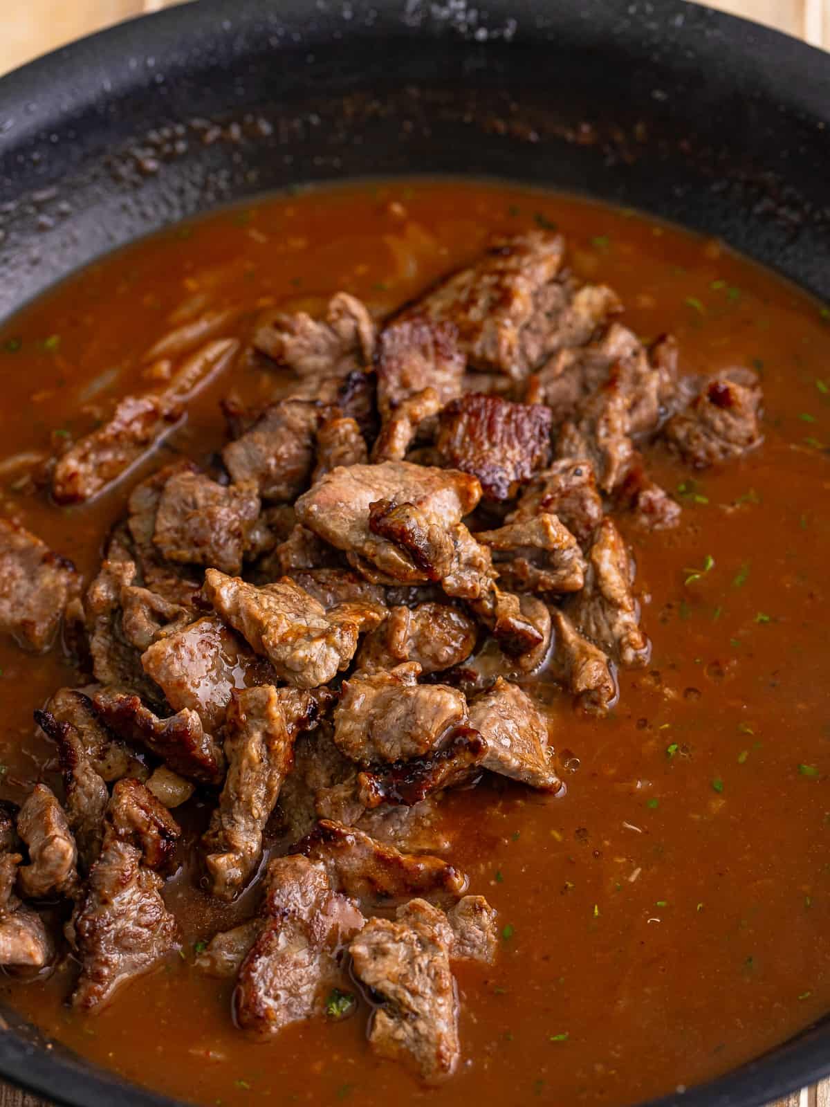 Returning the browned beef tips to the onion gravy.