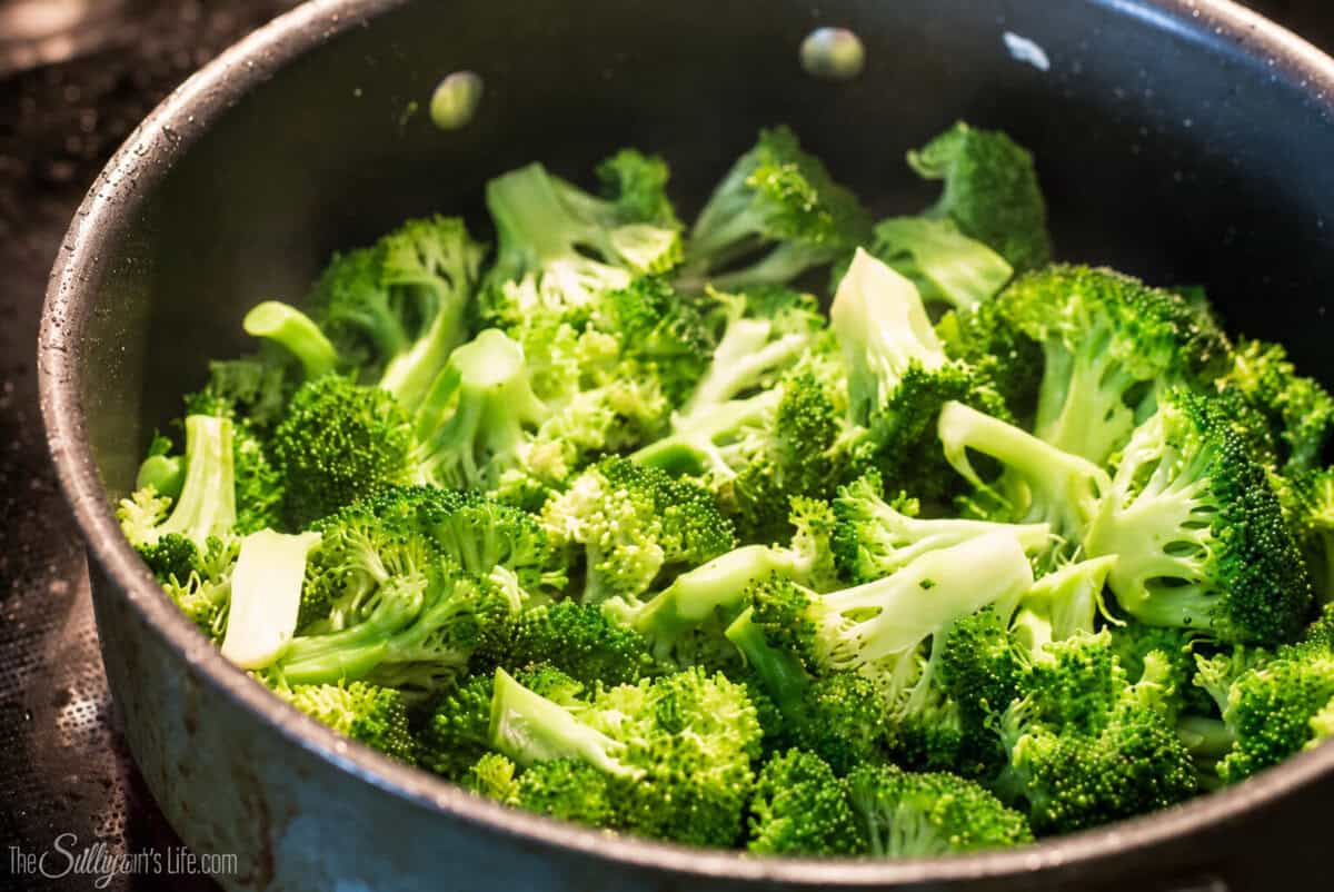 Fresh broccoli florets cut into bite sized pieces in a glass bowl, ready to add after the marinade soak.