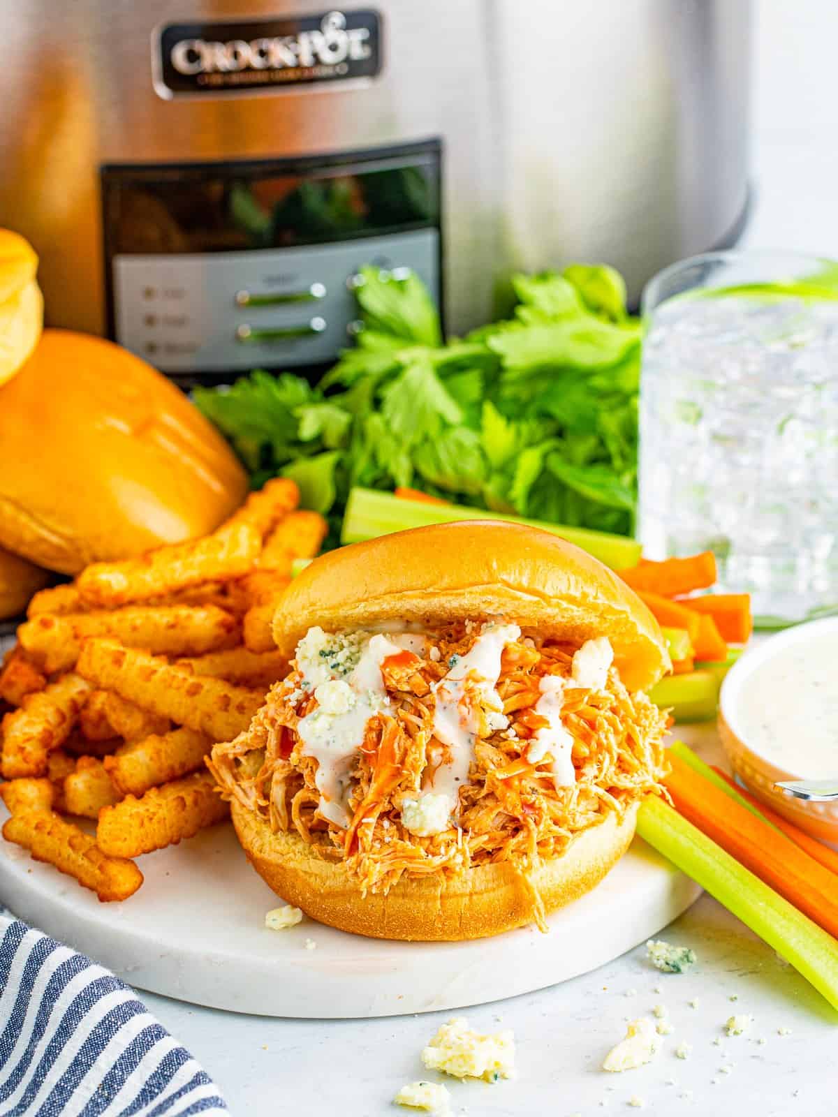 Slow cooker buffalo chicken sandwich on a brioche bun with ranch and blue cheese.