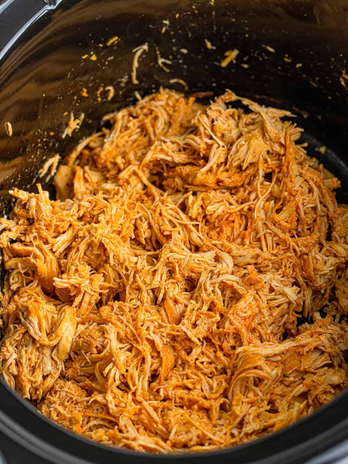 Shredded buffalo chicken in the slow cooker for buffalo chicken sandwiches.