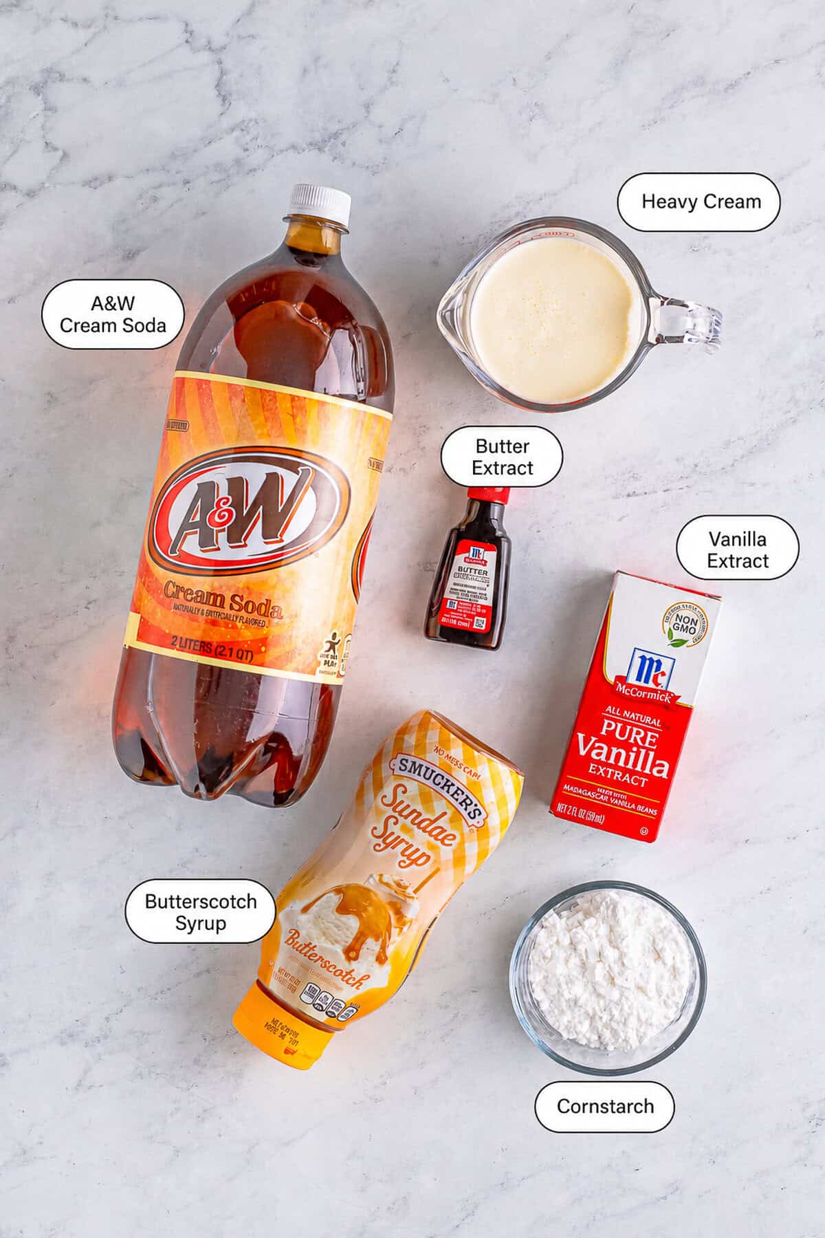 Ingredients arranged for a Butterbeer Recipe including cream soda, butterscotch syrup, butter extract, heavy cream, powdered sugar, and vanilla.