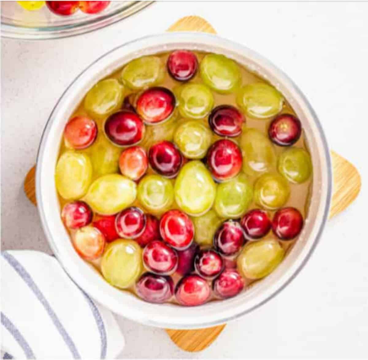 Coating fresh grapes in cooled simple syrup then transferring to a wire rack for Candied Grapes.