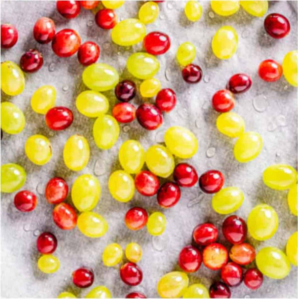 Rolling sticky grapes one at a time in a plate of granulated sugar to coat Candied Grapes.