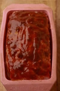Cheesy meatloaf topped with brown sugar ketchup sauce ready to bake.