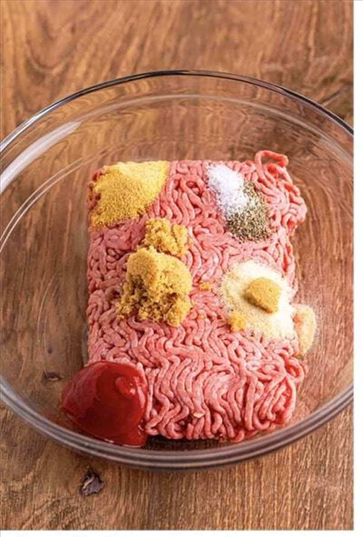 Ground beef, ketchup, Worcestershire sauce, and seasonings in a glass bowl to make cheeseburger sliders.