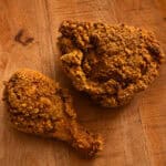 Cheesy fried chicken pieces with golden Chedz cracker crust on a serving plate.