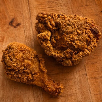Cheesy fried chicken pieces with golden Chedz cracker crust on a serving plate.
