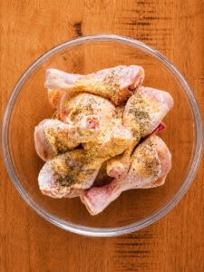 Raw chicken pieces seasoned with salt, pepper, garlic, and onion powder on a tray.