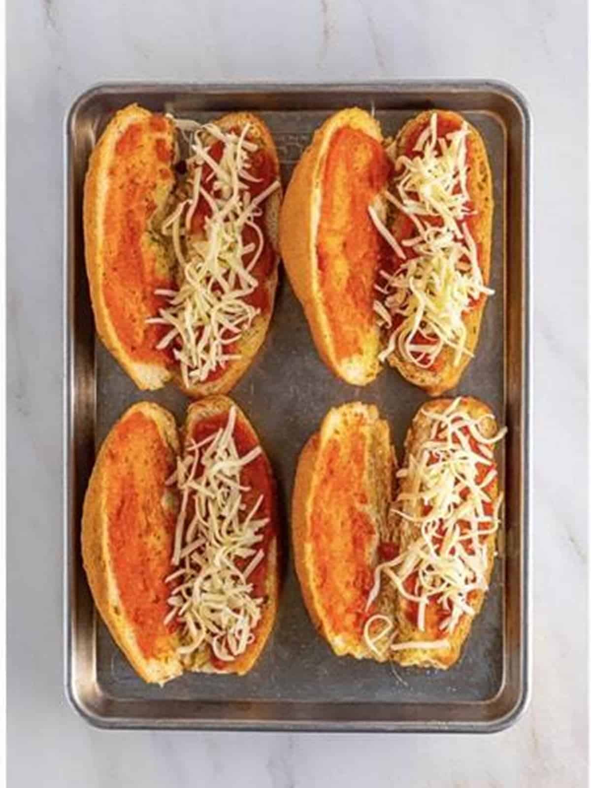 Shredded mozzarella added to the sauced hoagie rolls for chicken parmesan sandwiches.