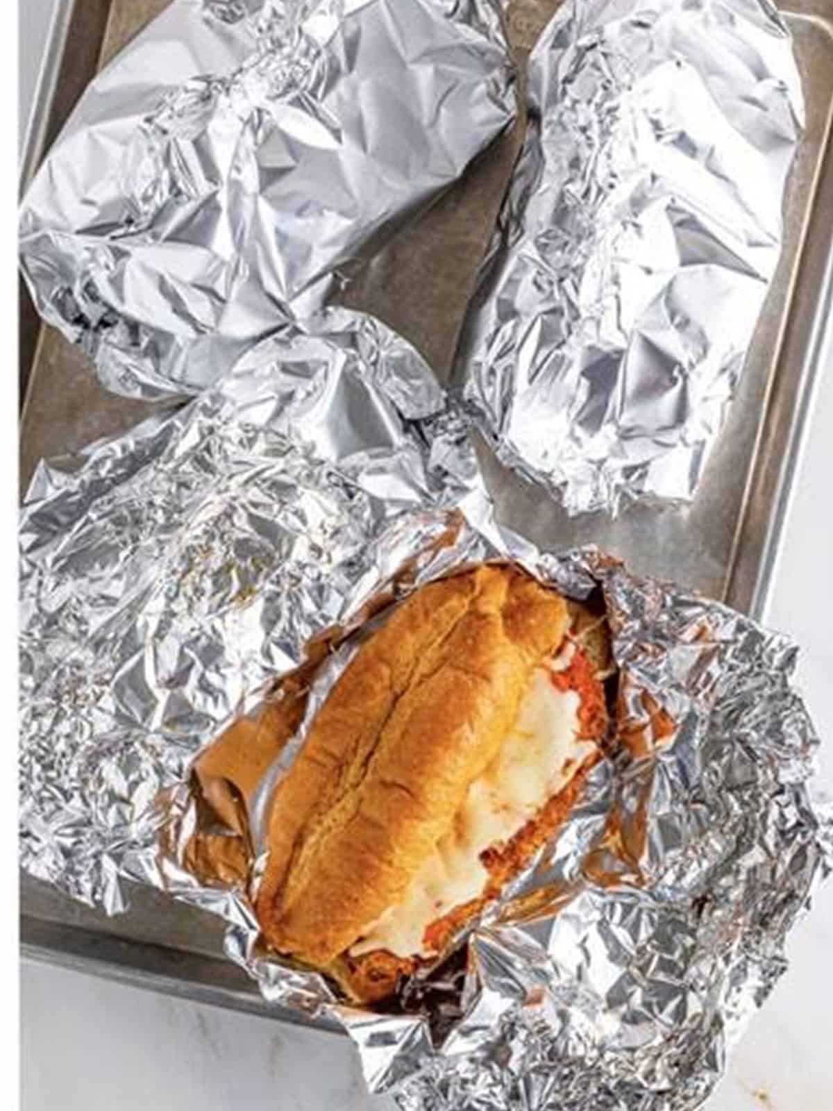 Foil wrapped chicken parmesan sandwiches baked until the cheese is melted.