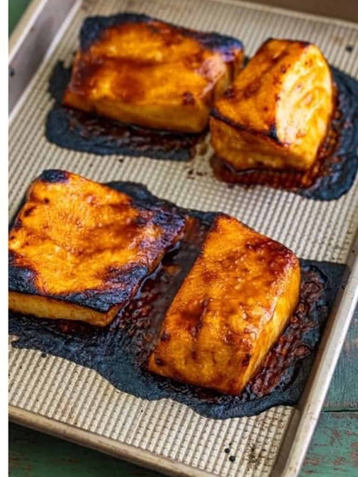 Broiled Chilean sea bass filets caramelized and glossy on the sheet tray.