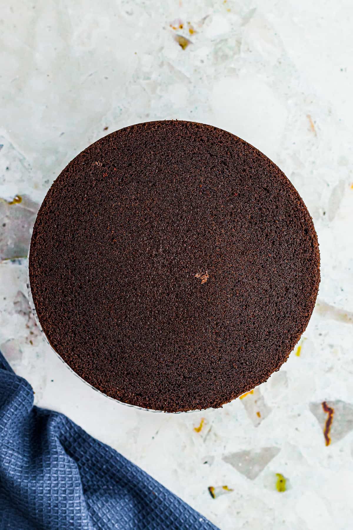 Chocolate buttercream being spread between two Chocolate Espresso Cake layers on a cake stand.