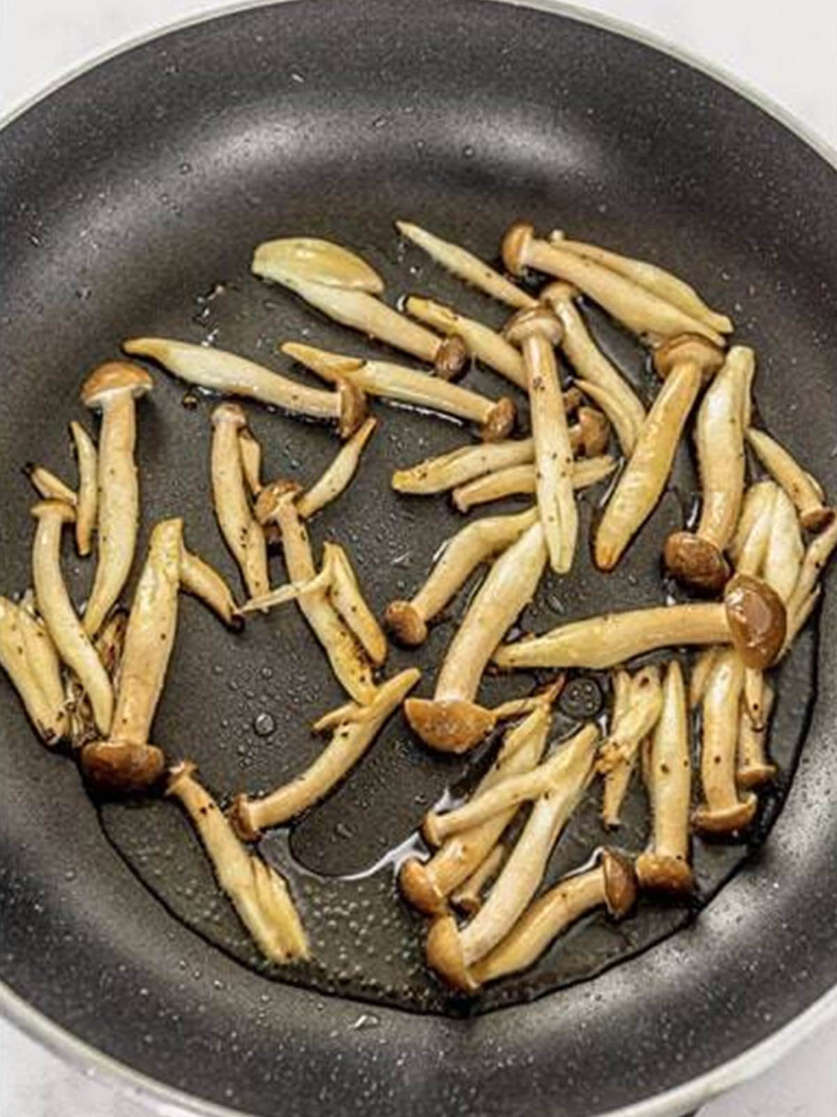 Shimeji mushrooms searing in a hot wok for Chow Mein with Ramen Noodles.